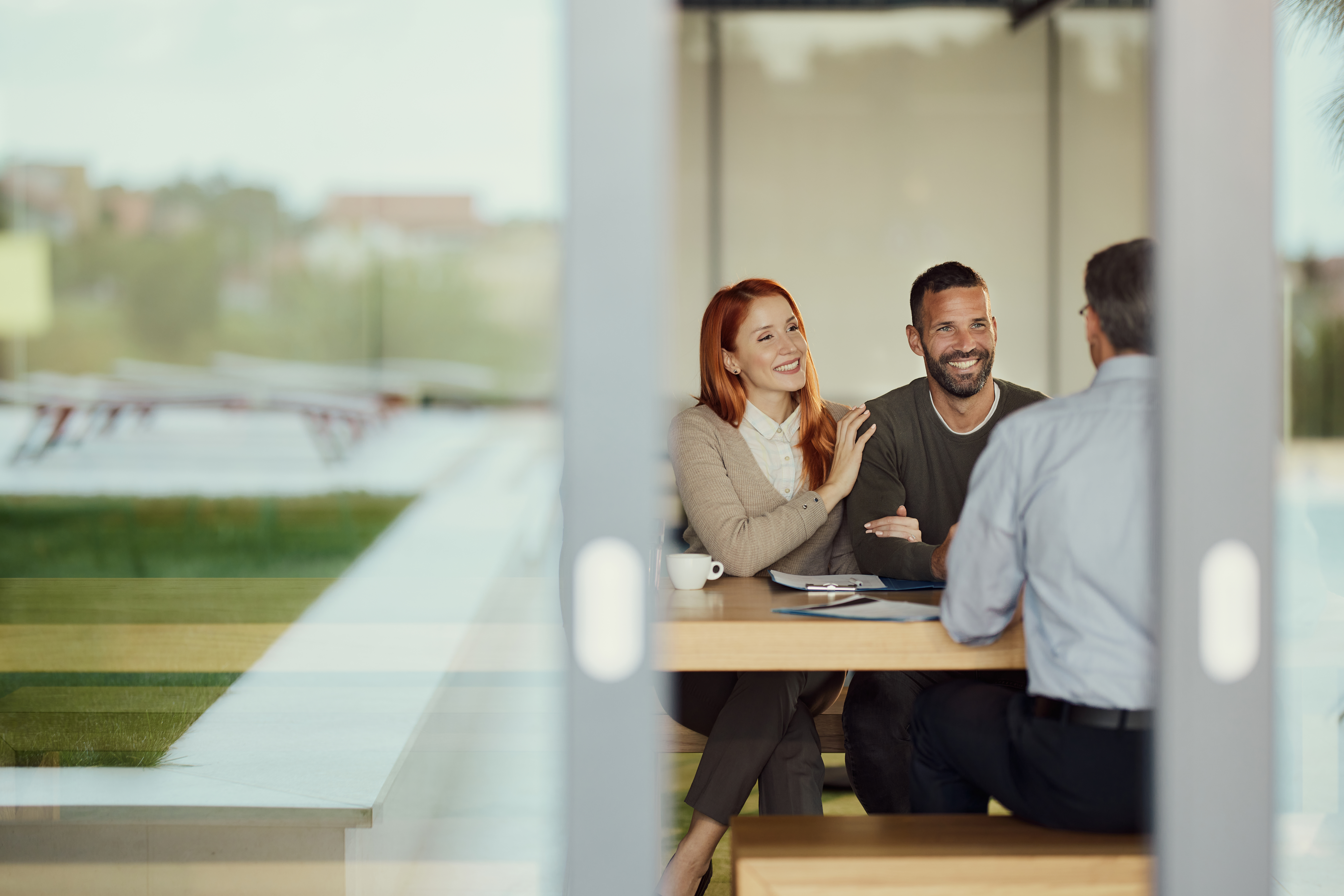 Ein glückliches Paar im Gespräch mit ihrem Ansprechpartner im Büro.