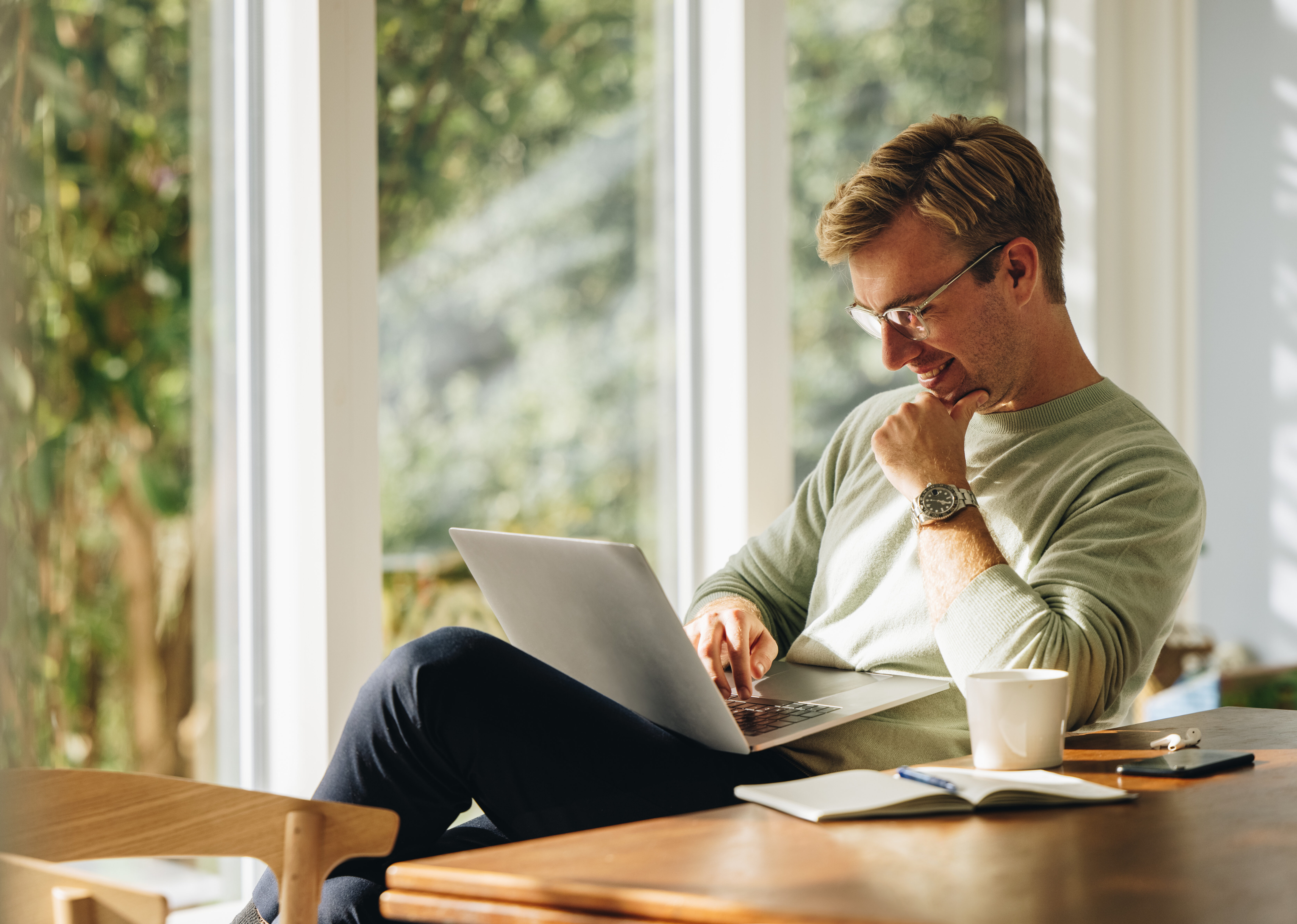 Junger Mann mit Laptop und lächelnd